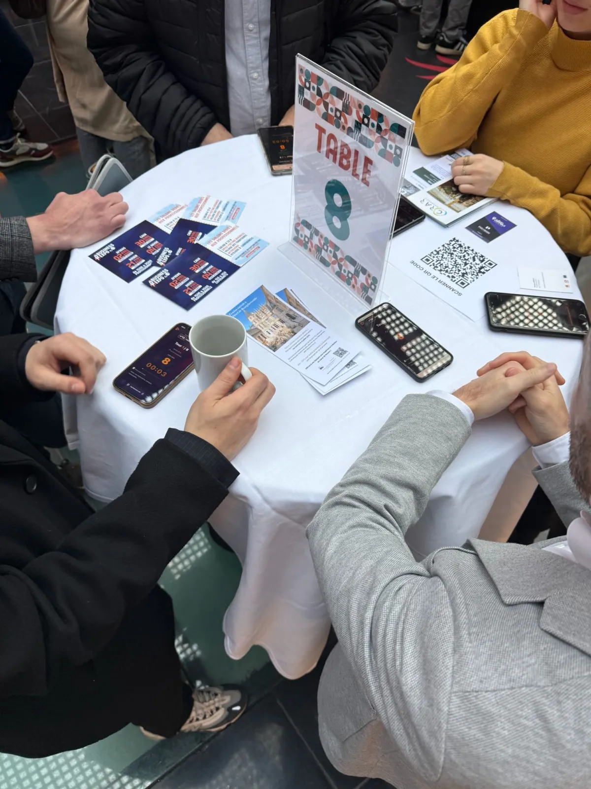 Participants en speed meeting autour d'une table numérotée avec QR code